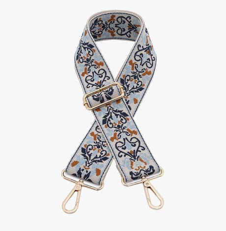Floral patterned bag strap with gold hardware on a white background