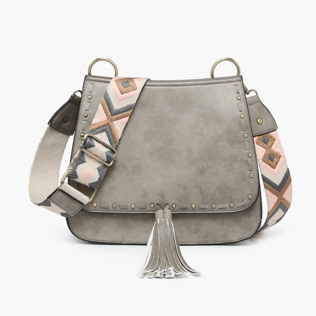 Gray suede handbag with patterned strap and tassel on a white background