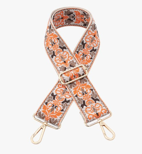 Floral patterned bag strap with gold hardware on a white background