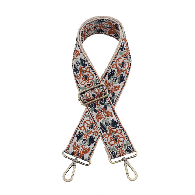 Floral patterned bag strap with metal hardware on a white background