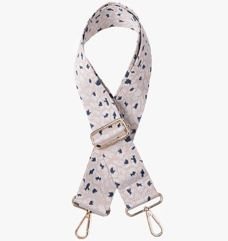 Patterned bag strap with gold hardware on a white background