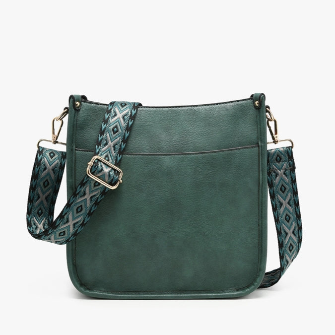 A dark green faux-leather crossbody bag with a patterned woven strap featuring geometric diamond motifs in green, gray, and white, and gold-tone hardware.
