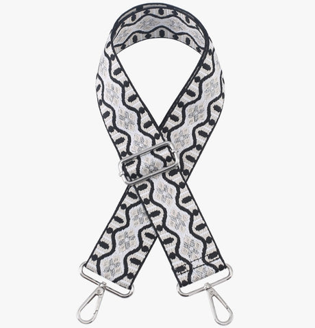 Patterned bag strap with metal hardware on a white background